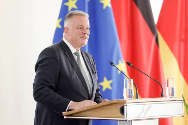 Ministerpräsident Gordon Schnieder am Rednerpult vor Fahnen anlässlich einer Feierstunde zur Verleihung von berufsbezogener Titel in der Staatskanzlei Rheinland-Pfalz 11.08.26 *** Prime Minister Gordon Schnieder at the lectern in front of flags during a ceremony to confer professional titles at the State Chancellery of Rhineland-Palatinate, August 26, 2011