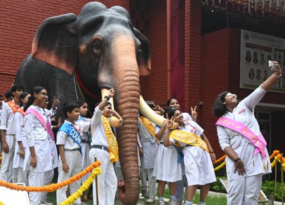 NEW DELHI, INDIA - AUGUST 11: Students at Kerala Education Society Senior Secondary School admire a newly unveiled elephant statue on the school premises along Shrimant Madhav Rao Scindia Marg on the eve of World Elephant Day on August 11, 2026 in New Delhi, India. The educational institution celebrated the environmental awareness occasion with enthusiasm, marking the formal inauguration of the majestic life-sized elephant sculpture installed at the school s primary entrance. (Photo by Sonu Mehta Hindustan Times) Students Pose With Life Size Elephant Statue On The Eve Of World Elephant Day