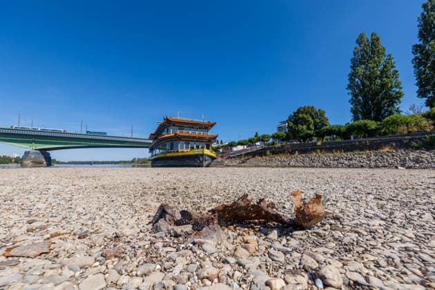 Niedrigwasser legt altes Metall im Rhein bei Bonn-Beuel frei Bildbeschreibung: Bonn, 12.08.2026: Durch das derzeitige extreme Niedrigwasser des Rheins werden am Beueler Rheinufer in Bonn alte Metallteile sichtbar, die zuvor über längere Zeit vom Wasser bedeckt waren. Das rostige Metall liegt nun auf dem freigelegten Bereich des Rheinbetts. Im Hintergrund ist erneut das auf dem trocken liegenden Uferbereich sichtbare Chinaschiff zu sehen. Der stark gesunkene Wasserstand gibt derzeit an mehreren Stellen des Rheinufers Gegenstände und Bereiche des Rheinbetts frei, die sonst unter Wasser liegen. Bonn Beuel Nordrhein-Westfalen Deutschland *** Low Water Levels Expose Old Metal in the Rhine Near Bonn-Beuel Image Description: Bonn, August