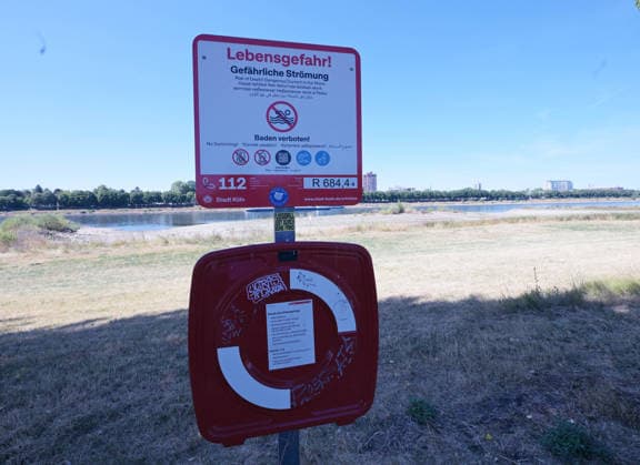 12.08.2026, xophax, öffentliches Leben, Köln, Rheinufer, Stadt Köln . Niedrigwasser. Rheinufer von Köln - Poll aus gesehen. Warnung vo dem Schwimmen im Rhein. Strömung. Köln *** August 12, 2026, xophax, public life, Cologne, banks of the Rhine, City of Cologne, low water levels on the banks of the Rhine in Cologne as seen from Poll, warning against swimming in the Rhine, current in Cologne