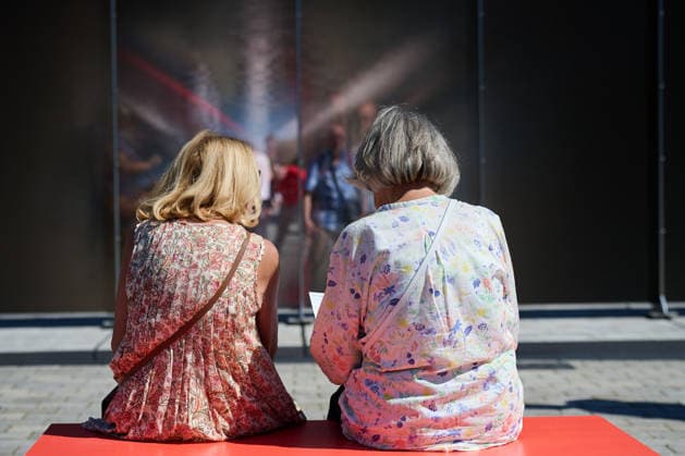 Ein temporaerer Gedenkort am Brandenburger Tor soll zum 65. Jahrestag des Mauerbaus an die deutsche Teilung erinnern (Foto vom 12.08.2026, im Bild: Menschen vor und hinter der Installation). Die rund drei Meter hohe und 30 Meter lange Installation des Kuenstlers Hubertus Hamm auf dem Platz des 18. Maerz soll an die einstigen Grenzanlagen erinnern. Je nach Perspektive wirkt die Wand aus Aluminium lichtundurchlaessig oder transparent. (Siehe epd-Meldung vom 12.08.2026) EDITORIAL USE ONLY *** A temporary memorial site at the Brandenburg Gate is intended to commemorate the division of Germany on the 65th anniversary of the construction of the Berlin Wall. Photo taken on August 12, 2026, showing people in front of and behind the installation. Th Copyright: epd-bild ChristianxDitsch D26D0812MauerbauInstallation135407