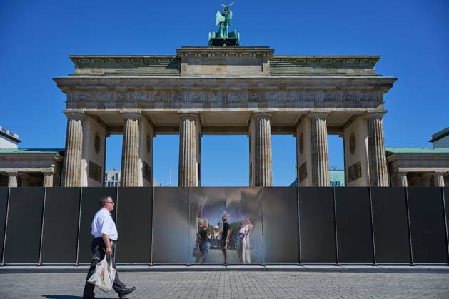 Ein temporaerer Gedenkort am Brandenburger Tor soll zum 65. Jahrestag des Mauerbaus an die deutsche Teilung erinnern (Foto vom 12.08.2026, im Bild: Menschen vor und hinter der Installation). Die rund drei Meter hohe und 30 Meter lange Installation des Kuenstlers Hubertus Hamm auf dem Platz des 18. Maerz soll an die einstigen Grenzanlagen erinnern. Je nach Perspektive wirkt die Wand aus Aluminium lichtundurchlaessig oder transparent. (Siehe epd-Meldung vom 12.08.2026) EDITORIAL USE ONLY *** A temporary memorial site at the Brandenburg Gate is intended to commemorate the division of Germany on the 65th anniversary of the construction of the Berlin Wall. Photo taken on August 12, 2026, showing people in front of and behind the installation. Th Copyright: epd-bild ChristianxDitsch D26D0812MauerbauInstallation142201