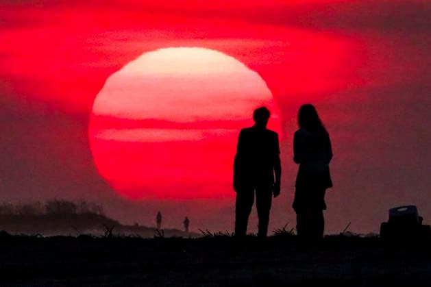 August 12, 2026, Isle Of Palms, Sc, United States: A couple silhouetted by the sunrise, stop to watch as the massive ball climbs over the Atlantic Ocean horizon, August 12, 2026 in Isle of Palms, South Carolina. The Charleston area is currently under a heat advisory with temperatures in the 90Ã¢â‚¬â ¢s and a heat index of 115-degrees. Isle Of Palms United States  - ZUMAe02_ 20260812_zaf_e02_002 Copyright: xRichardxEllisx