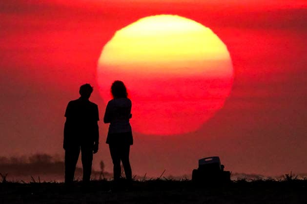 August 12, 2026, Isle Of Palms, Sc, United States: A couple silhouetted by the sunrise, stop to watch as the massive ball climbs over the Atlantic Ocean horizon, August 12, 2026 in Isle of Palms, South Carolina. The Charleston area is currently under a heat advisory with temperatures in the 90Ã¢â‚¬â ¢s and a heat index of 115-degrees. Isle Of Palms United States  - ZUMAe02_ 20260812_zaf_e02_004 Copyright: xRichardxEllisx