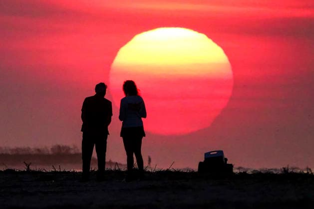 August 12, 2026, Isle Of Palms, Sc, United States: A couple silhouetted by the sunrise, stop to watch as the massive ball climbs over the Atlantic Ocean horizon, August 12, 2026 in Isle of Palms, South Carolina. The Charleston area is currently under a heat advisory with temperatures in the 90Ã¢â‚¬â ¢s and a heat index of 115-degrees. Isle Of Palms United States - ZUMAe02_ 20260812_zaf_e02_003 Copyright: xRichardxEllisx