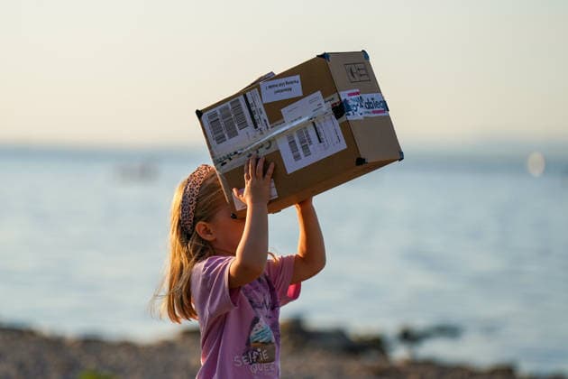 Altenrhein, Bodensee, Schweiz: Mädchen beobachtet eine Sonnenfinsternis mit einer selbstgebauten Lochkamera aus einem Karton. Das Kind richtet die improvisierte Projektionshilfe zur Sonne, im Hintergrund der Bodensee. Sonnenfinsternis, partielle Sonnenfinsternis, Sofi, Astronomie, Sonne, Lochkamera, Projektionsmethode, Augenschutz, Kind, Mädchen, Experiment, Naturphänomen, Wissenschaft, Altenrhein, Bodensee, St. Gallen, Schweiz. *** Altenrhein, Lake Constance, Switzerland: A girl observes a solar eclipse using a homemade pinhole camera made from a cardboard box. The child points the improvised projection device toward the sun; Lake Constance is visible in the background. Solar eclipse, partial solar eclipse, Sofi, astronomy, sun, pin Copyright: xJOERANxSTEINSIEKx