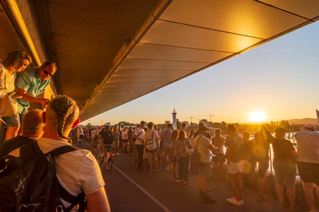people with eclipse glasses watching partial solar eclipse on bridge Reichsbrücke, at subway U1 station entrance Donauinsel Vienna 22. Donaustadt Wien Austria