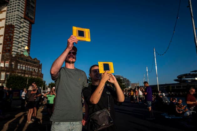 August 12, 2026, Rotterdam, South Holland, The Netherlands Holland: A couple holds homemade eye protection as they watch a solar eclipse over Holland. 12 August 2026, Rotterdam, the Netherlands. Hundreds of Dutch spectators witnessed a partial solar eclipse seen from the Wilhelminapier as the Moon blocked nearly 90% of the Sun over the Nieuwe Maas. Rotterdam The Netherlands Holland - ZUMAp202 20260812_zip_p202_015 Copyright: xJamesxPetermeierx