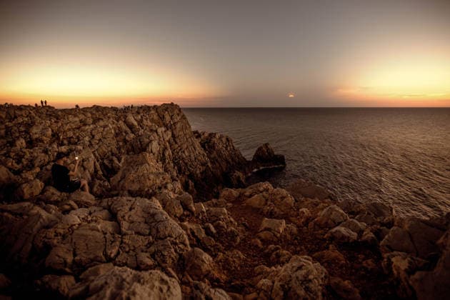 August 12, 2026, Ciutadella, Balearic Islands Menorca, Spain: People gather along the rocky coast during a total solar eclipse at Punta Nati on the Spanish Balearic island of Menorca. Ciutadella Spain - ZUMAo105 20260812_fap_o105_021 Copyright: xMatthiasxOesterlex