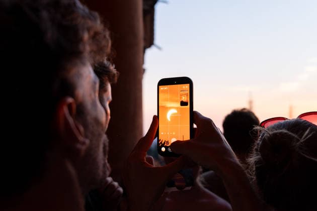 IPA87432150 - A man uses his phone to watch a solar eclipse at the Sanctuary of the Madonna di San Luca. Bologna, Italy, August 8, 2026  Copyright: xLeonardoxGaravaglia LiveMediax xx 87432150