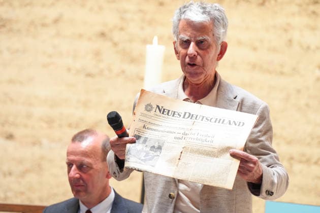 Gedenkveranstaltung 65. Jahrestag des Berliner Mauerbaus Joerg Hildebrandt haelt die historische Tageszeitung und Titelseite der Zeitung Neues Deutschland hoch und zeiht die Schlagzeile zum Kommunismus bei der Gedenkveranstaltung zum 65. Jahrestag des Berliner Mauerbaus, Berlin, 13.08.2026 Berlin Berlin Deutschland *** Commemoration of the 65th Anniversary of the Construction of the Berlin Wall: Jörg Hildebrandt holds up the historic daily newspaper *Neues Deutschland* and its front page, pointing to the headline about communism at the commemoration marking the 65th anniversary of the construction of the Berlin Wall, Berlin, August 13, 2026 Berlin Berlin Germany