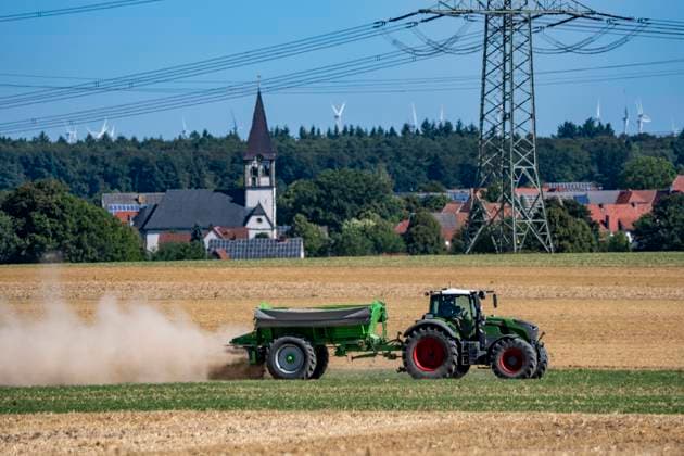 Trecker mit Mineraldüngerstreuer, bearbeitet ein abgeerntetes Getreidefeld, streut mineralischen Dünger, Kalk aus, um die Qualität des Boden für eine erneute Nutzung, Aussaat zu steigern, bei Marsberg-Meerhof, NRW, Deutschland Feldarbeit *** A tractor equipped with a mineral fertilizer spreader is working a harvested grain field, spreading mineral fertilizer and lime to improve soil quality for future use and planting, at Marsberg Meerhof, North Rhine-Westphalia, Germany—field work