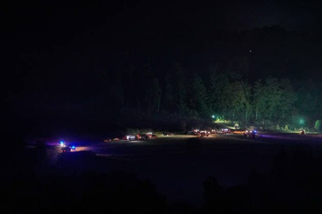 Helminghausen, Marsberg, Nordrhein-Westfalen, Deutschland, Europa: Weitwinkelaufnahme eines nächtlichen Waldbrandeinsatzes mit zahlreichen Feuerwehrfahrzeugen und Einsatzkräften auf einer Freifläche am Waldrand. Mobile Beleuchtung und Blaulicht markieren den Bereitstellungsraum, während die Feuerwehr die Löscharbeiten und die Einsatzkoordination in unwegsamem Gelände fortsetzt. *** Helminghausen, Marsberg, North Rhine-Westphalia, Germany, Europe Wide-angle shot of a nighttime forest fire operation featuring numerous fire trucks and emergency personnel in an open area at the edge of the forest. Mobile lighting and blue lights mark the staging area, while firefighters continue firefighting operations and coordinate the response in r Copyright: xAymanxAlahmedx