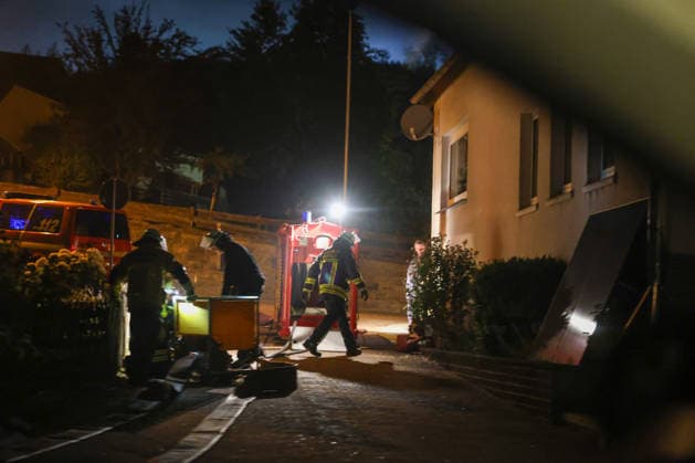Helminghausen, Marsberg, Nordrhein-Westfalen, Deutschland, Europa: Feuerwehrkräfte bereiten in einer Wohnstraße während eines nächtlichen Waldbrandeinsatzes nahe der Diemeltalsperre ihre Ausrüstung vor. Einsatzfahrzeuge, Beleuchtung und Schlauchmaterial stehen vor einem Wohnhaus bereit, während die Maßnahmen zur Brandbekämpfung koordiniert werden. *** Helminghausen, Marsberg, North Rhine-Westphalia, Germany, Europe: Firefighters are preparing their equipment on a residential street during a nighttime forest fire operation near the Diemel Dam. Emergency vehicles, lighting, and hoses are set up in front of a residential building while firefighting efforts are being coordinated. Copyright: xAymanxAlahmedx