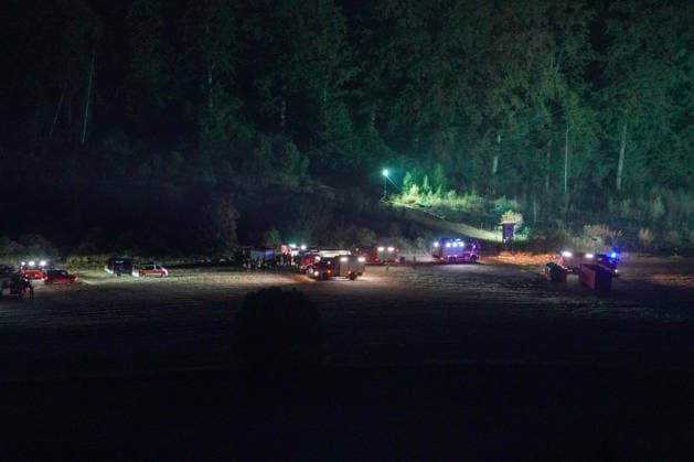 Helminghausen, Marsberg, Nordrhein-Westfalen, Deutschland, Europa: Feuerwehrfahrzeuge und Einsatzkräfte haben während eines nächtlichen Waldbrandeinsatzes einen Bereitstellungsraum auf einer Freifläche am Waldrand eingerichtet. Mobile Flutlichtanlagen beleuchten den Einsatzbereich, während die Einsatzleitung und Löschfahrzeuge den groß angelegten Feuerwehreinsatz koordinieren. *** Helminghausen, Marsberg, North Rhine-Westphalia, Germany, Europe Fire trucks and emergency personnel set up a staging area in an open space at the edge of the forest during a nighttime forest fire operation. Mobile floodlights illuminate the scene, while incident command and fire trucks coordinate the large-scale firefighting operation. Copyright: xAymanxAlahmedx