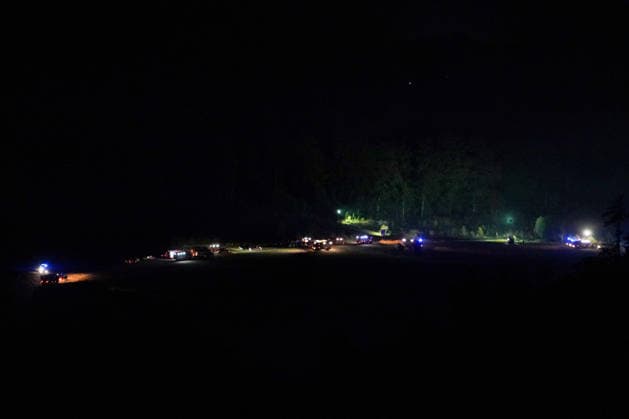 Helminghausen, Marsberg, Nordrhein-Westfalen, Deutschland, Europa: Weitwinkelaufnahme eines nächtlichen Waldbrandeinsatzes mit zahlreichen Feuerwehrfahrzeugen und Einsatzkräften auf einer Freifläche am Waldrand. Blaulicht und mobile Flutlichtanlagen markieren den weitläufigen Bereitstellungsraum, während die Feuerwehr die Löscharbeiten und die Einsatzkoordination in schwierigem Gelände fortsetzt. *** Helminghausen, Marsberg, North Rhine-Westphalia, Germany, Europe Wide-angle shot of a nighttime forest fire operation featuring numerous fire trucks and emergency personnel in an open area at the edge of the forest. Blue lights and mobile floodlights illuminate the expansive staging area, while firefighters continue firefighting oper Copyright: xAymanxAlahmedx