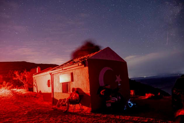 Perseid Meteor Shower Over Izmir A person sits outside a small building bearing a crescent-and-star emblem beneath a star-filled sky near Sarpincik Lighthouse in Karaburun district of Izmir, Turkey, on August 13, 2026. The annual Perseid meteor shower, produced as Earth passes through debris left by comet Swift-Tuttle, peaked overnight from August 12 into the early hours of August 13, drawing skywatchers to dark viewing points to observe one of the year™s best-known meteor displays. Izmir Izmir Turkey Copyright: xMuratxKocabasx