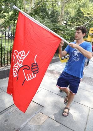 August 13, 2026, New York, New York, USA: A man with a Democratic Socialist of American (DSA) flag joins the Amazon Teamsters and Allies picket outside of City Hall for passage of the Delivery Protection Act. The Delivery Protection Act would require companies like Amazon to hire its workforce directly, essentially making Amazons corrupt third-party Delivery Service Partner model illegal in New York City. New York USA  - ZUMAk03_ 20260813_zaf_k03_066 Copyright: xNancyxKaszermanx