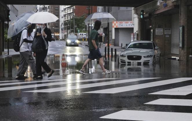 Aftermath of torrential rain in eastern Japan People walk by a submerged vehicle on a flooded road in Chiba, east of Tokyo, in the early morning of Aug. 14, 2026, following overnight torrential rain. Japan s weather agency issued its highest Level 5 warning for downpours in parts of Chiba Prefecture.  A14AA0005625739P