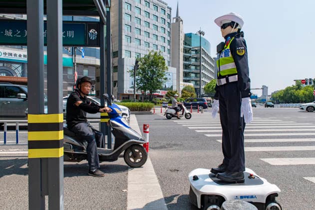 YONGKANG, CHINA - AUGUST 14: A robot traffic police officer advises riders to wear safety helmets at an intersection on August 14, 2026 in Yongkang, Jinhua, Zhejiang Province of China. Local authorities have launched a trial operation of robot traffic police to assist with road safety management.  Copyright: xVCGx 111659918412