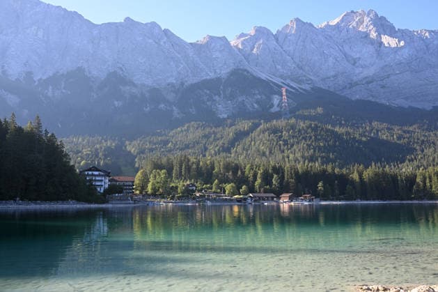 Wetterfeature, Morgenstille am Eibsee: Unterhalb der Zugspitze liegt der See bei Grainau nahe Garmisch-Partenkirchen in den frühen Stunden noch ruhig und nahezu unberührt. Doch an heißen Sommertagen ändert sich das Bild häufig schon ab Mittag. Dann strömen zahlreiche Ausflügler und Urlauber an den durch soziale Medien weltweit bekannt gewordenen Bergsee. Der zunehmende Massentourismus sorgt regelmäßig für einen regelrechten Besucheransturm. Unter dem hohen Verkehrsaufkommen, zugeparkten Straßen und dem großen Andrang leiden zunehmend auch die Anwohner in Grainau und rund um den Eibsee. Grainau Bayern Deutschland Grainau *** Weather Feature, Morning Stillness at Eibsee. Nestled below the Zugspitze near Grainau, close to Garmisch- Copyright: x xonw-imagesx xMariusxBullingx