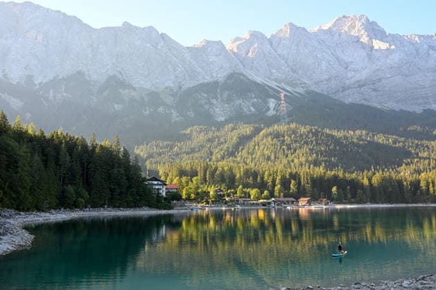 Wetterfeature, Morgenstille am Eibsee: Unterhalb der Zugspitze liegt der See bei Grainau nahe Garmisch-Partenkirchen in den frühen Stunden noch ruhig und nahezu unberührt. Doch an heißen Sommertagen ändert sich das Bild häufig schon ab Mittag. Dann strömen zahlreiche Ausflügler und Urlauber an den durch soziale Medien weltweit bekannt gewordenen Bergsee. Der zunehmende Massentourismus sorgt regelmäßig für einen regelrechten Besucheransturm. Unter dem hohen Verkehrsaufkommen, zugeparkten Straßen und dem großen Andrang leiden zunehmend auch die Anwohner in Grainau und rund um den Eibsee. Grainau Bayern Deutschland Grainau *** Weather Feature, Morning Stillness at Eibsee. Nestled below the Zugspitze near Grainau, close to Garmisch- Copyright: x xonw-imagesx xMariusxBullingx