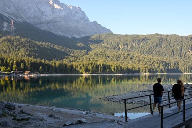 Wetterfeature, Morgenstille am Eibsee: Unterhalb der Zugspitze liegt der See bei Grainau nahe Garmisch-Partenkirchen in den frühen Stunden noch ruhig und nahezu unberührt. Doch an heißen Sommertagen ändert sich das Bild häufig schon ab Mittag. Dann strömen zahlreiche Ausflügler und Urlauber an den durch soziale Medien weltweit bekannt gewordenen Bergsee. Der zunehmende Massentourismus sorgt regelmäßig für einen regelrechten Besucheransturm. Unter dem hohen Verkehrsaufkommen, zugeparkten Straßen und dem großen Andrang leiden zunehmend auch die Anwohner in Grainau und rund um den Eibsee. Grainau Bayern Deutschland Grainau *** Weather Feature, Morning Stillness at Eibsee. Nestled below the Zugspitze near Grainau, close to Garmisch- Copyright: x xonw-imagesx xMariusxBullingx