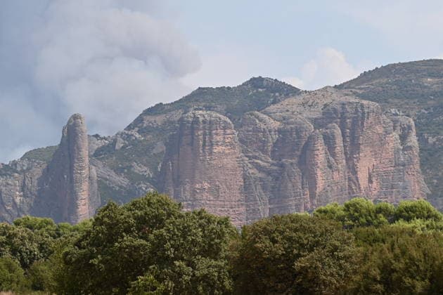 The spread of the fire in Huesca forces the evacuation of the monastery of San Juan de la Pena Columns of smoke caused by a wildfire in Los Mayos de Riglos on August 14, 2026, in Las Penas de Riglos, Hoya de Huesca, Huesca, Aragón, Spain. The fire that broke out at 12:37 p.m. this Monday in Las Penas de Riglos, Huesca, has already burned more than 9,000 hectares and forced the preventive evacuation of sixteen towns and a total of 830 people. This Thursday, the flames surrounded the old monastery of San Juan de la Pena, though they did not damage the structure. Early this morning, the regional government issued an evacuation order for four more municipalities, in addition to the twelve from yesterday: these are the towns of Santa María de L  Copyright: xRamonxCometx 7713977