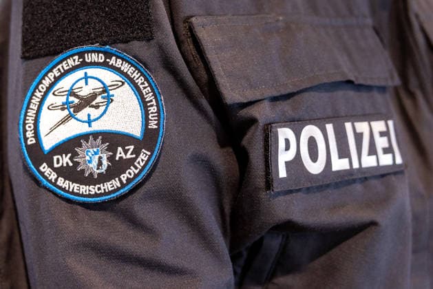 Drohnendetektion und -abwehr der Bayerischen Polizei, Flughafen Nürnberg, 14.08.2026 Ärmelabzeichen des Drohnenkompetenz- und -abwehrzentrums (DKAZ) der Bayerischen Polizei auf einer Polizeiuniform, daneben der Schriftzug POLIZEI. Die Polizei informiert über die Möglichkeiten zur Drohnendetektion und -abwehr sowie den geplanten Ausbau von Technik und Personal. Nürnberg Flughafen Bayern Deutschland *** Drone Detection and Defense by the Bavarian Police, Nuremberg Airport, August 14, 2026. Sleeve insignia of the Bavarian Police’s Drone Competence and Defense Center (DKAZ) on a police uniform, next to the word POLIZEI. The police are providing information on drone detection and defense capabilities, as well as the planned expansion of t 20260814-286A5131-M4000