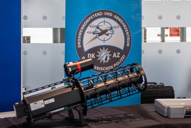 Drohnendetektion und -abwehr der Bayerischen Polizei, Flughafen Nürnberg, 14.08.2026 Ein tragbares, schultergestütztes Störsender-System des Typs HP 47+ PRO V7 (Counter-UAV-Jammer) ist auf einem Tisch ausgestellt. Im Hintergrund verweist das Logo des Drohnenkompetenz- und -abwehrzentrums der Bayerischen Polizei auf den Einsatzbereich der Technik. Nürnberg Flughafen Bayern Deutschland *** Drone Detection and Defense by the Bavarian Police, Nuremberg Airport, August 14, 2026 A portable, shoulder-mounted jammer system, the HP 47 PRO V7 Counter UAV Jammer, is on display on a table. In the background, the logo of the Bavarian Police’s Drone Competence and Defense Center indicates the technology’s area of application. Nuremberg Airport, Bavar 20260814-286A5347-M4000