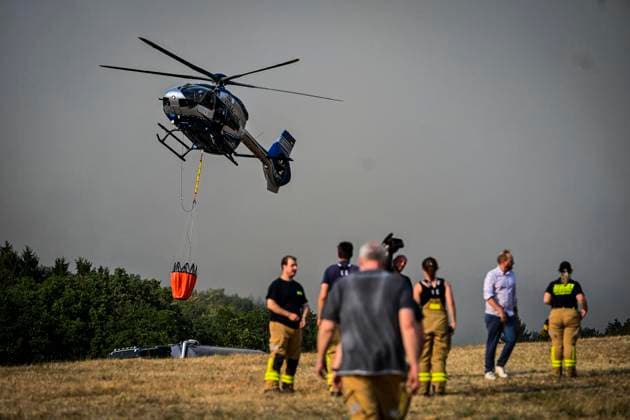 Waldbrände im Kreis Düren in der Eifel Hürtgenwald ** NUR FÜR REDAKTIONELLE ZWECKE ** EDITORIAL USE ONLY **<p>Hubschrauber im Dauereinsatz, beladen ihre Wassertanks in Großhau auf einem Feld , im Hintergrund Rauch vom Waldbrand , am Freitag, dem 14 08 2026 Waldbrände im Kreis Düren in der Eifel Hürtgenwald Deutschland NRW Essen Copyright: KerstinxKokoska *** Forest fires in the Düren district in the Eifel region, Hürtgenwald ** FOR EDITORIAL USE ONLY ** ** EDITORIAL USE ONLY ** Helicopters in continuous operation are filling their water tanks in a field in Großhau, with smoke from the forest fire visible in the background, on Friday, August 14, 2026. Forest fires in the Düren district in the Eifel region, Hürtgenwald, Germa Copyright: KerstinxKokoska doc875pp0r80054zu2hoov ,EDITORIAL USE ONLY