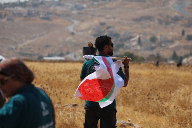 Activists Remove Flags From Beit Sahour An activist carries a flag bearing a watermelon motif while walking across open ground in Beit Sahour, east of Bethlehem in the occupied West Bank, on August 14, 2026. The activists said settlers had placed the symbols on the house after October 7, 2023, in what they described as an attempt to seize control of the property, and that settlers opened fire toward them as the items were removed, with no injuries reported. Bethlehem West Bank Palestinian Territories Copyright: xMosabxShawerx