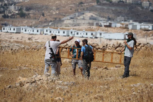 Activists Remove Flags From Beit Sahour Activists handle a wooden ladder in a field in Beit Sahour, east of Bethlehem in the occupied West Bank, on August 14, 2026. The activists said settlers had placed the symbols on the house after October 7, 2023, in what they described as an attempt to seize control of the property, and that settlers opened fire toward them as the items were removed, with no injuries reported. Bethlehem West Bank Palestinian Territories Copyright: xMosabxShawerx