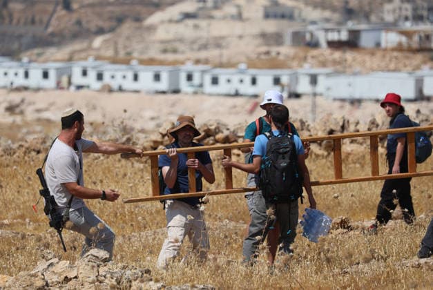 Activists Remove Flags From Beit Sahour Activists carry a wooden ladder across rocky ground in Beit Sahour, east of Bethlehem in the occupied West Bank, on August 14, 2026. The activists said settlers had placed the symbols on the house after October 7, 2023, in what they described as an attempt to seize control of the property, and that settlers opened fire toward them as the items were removed, with no injuries reported. Bethlehem West Bank Palestinian Territories Copyright: xMosabxShawerx