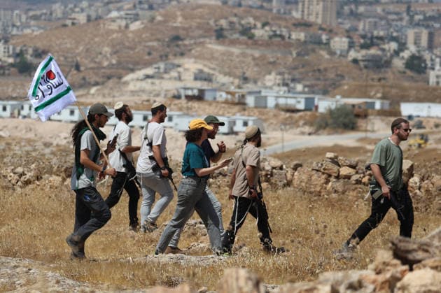 Activists Remove Flags From Beit Sahour Activists carrying a flag walk near armed men in Beit Sahour, east of Bethlehem in the occupied West Bank, on August 14, 2026. The activists said settlers had placed the symbols on the house after October 7, 2023, in what they described as an attempt to seize control of the property, and that settlers opened fire toward them as the items were removed, with no injuries reported. Bethlehem West Bank Palestinian Territories Copyright: xMosabxShawerx