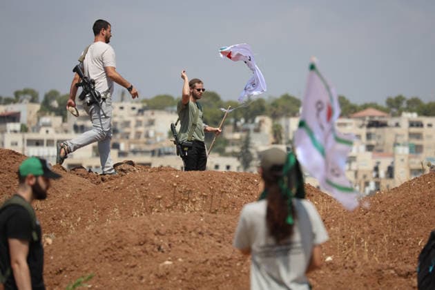 Activists Remove Flags From Beit Sahour Armed men stand on a mound of earth as activists carrying flags remain nearby in Beit Sahour, east of Bethlehem in the occupied West Bank, on August 14, 2026. The activists said settlers had placed the symbols on the house after October 7, 2023, in what they described as an attempt to seize control of the property, and that settlers opened fire toward them as the items were removed, with no injuries reported. Bethlehem West Bank Palestinian Territories Copyright: xMosabxShawerx