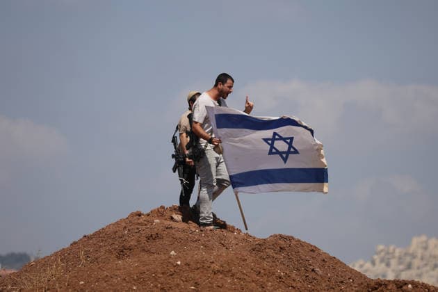 Activists Remove Flags From Beit Sahour Armed men hold an Israeli flag on top of a mound of earth in Beit Sahour, east of Bethlehem in the occupied West Bank, on August 14, 2026. The activists said settlers had placed the symbols on the house after October 7, 2023, in what they described as an attempt to seize control of the property, and that settlers opened fire toward them as the items were removed, with no injuries reported. Bethlehem West Bank Palestinian Territories Copyright: xMosabxShawerx