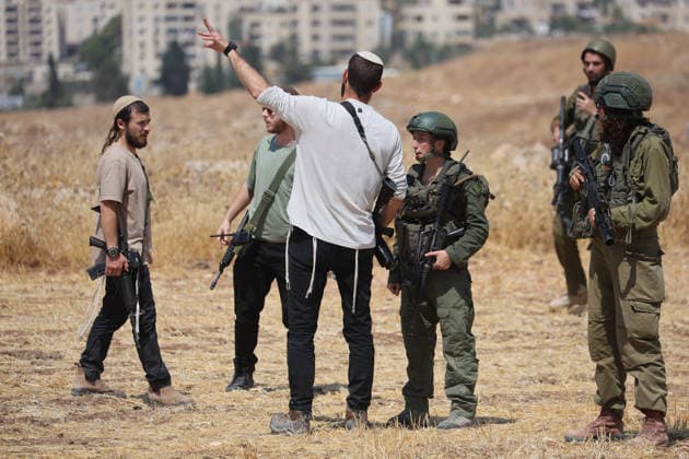 Activists Remove Flags From Beit Sahour Armed men speak with uniformed security personnel in an open field in Beit Sahour, east of Bethlehem in the occupied West Bank, on August 14, 2026. The activists said settlers had placed the symbols on the house after October 7, 2023, in what they described as an attempt to seize control of the property, and that settlers opened fire toward them as the items were removed, with no injuries reported. Bethlehem West Bank Palestinian Territories Copyright: xMosabxShawerx