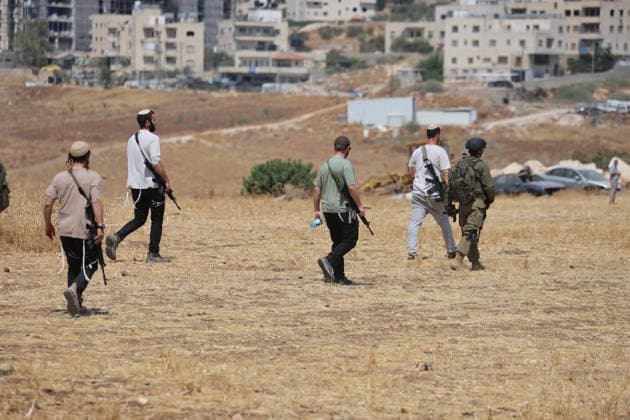 Activists Remove Flags From Beit Sahour Armed men and uniformed security personnel walk across an open field in Beit Sahour, east of Bethlehem in the occupied West Bank, on August 14, 2026. The activists said settlers had placed the symbols on the house after October 7, 2023, in what they described as an attempt to seize control of the property, and that settlers opened fire toward them as the items were removed, with no injuries reported. Bethlehem West Bank Palestinian Territories Copyright: xMosabxShawerx