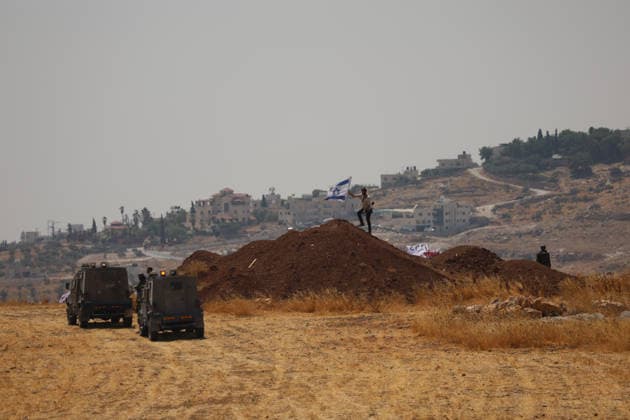 Activists Remove Flags From Beit Sahour Two vehicles stand in a dry field as people remain on a mound of earth where an Israeli flag is visible in Beit Sahour, east of Bethlehem in the occupied West Bank, on August 14, 2026. The activists said settlers had placed the symbols on the house after October 7, 2023, in what they described as an attempt to seize control of the property, and that settlers opened fire toward them as the items were removed, with no injuries reported. Bethlehem West Bank Palestinian Territories Copyright: xMosabxShawerx