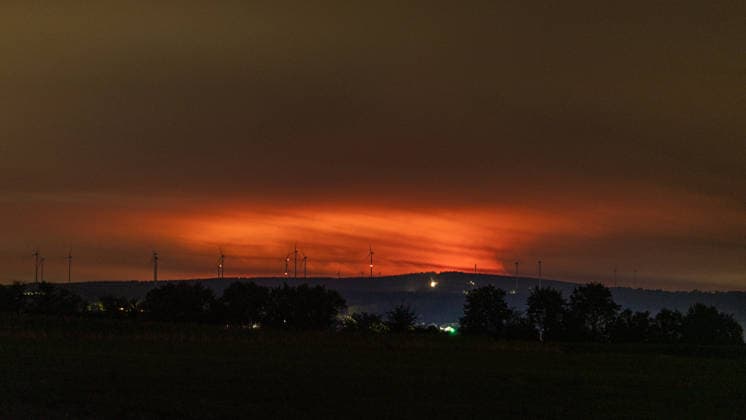 Nachtaufnahme: Waldbrand im Hohen Venn hinter Windkrafträdern bei Kleinhau Nachtaufnahme aus Kleinhau (Gemeinde Hürtgenwald): Am Horizont, rund 26 Kilometer entfernt in Belgien, erhellt rötlicher Flammenschein den Brandrauch des Großbrands im Hohen Venn bei Drossart (Gemeinde Baelen) dort ist die Fläche seit dem Nachmittag von rund 1 auf etwa 80 Hektar gewachsen, ein Notfallplan der Provinz Lüttich wurde ausgerufen. Im Vordergrund sind Windkrafträder zu erkennen. Hürtgenwald Kleinhau Nordrhein-Westfalen Deutschland *** Nighttime photo of a forest fire in the High Fens behind wind turbines near Kleinhau. Nighttime photo taken from Kleinhau, in the municipality of Hürtgenwald. On the horizon, about 26 kilometers away in Belgium, a Copyright: xMarcxJohnx
