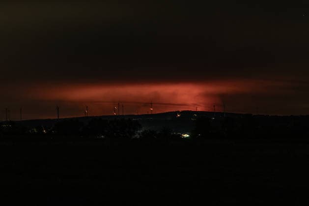 Nachtaufnahme: Waldbrand im Hohen Venn hinter Windkrafträdern bei Kleinhau Nachtaufnahme aus Kleinhau (Gemeinde Hürtgenwald): Am Horizont, rund 26 Kilometer entfernt in Belgien, erhellt rötlicher Flammenschein den Brandrauch des Großbrands im Hohen Venn bei Drossart (Gemeinde Baelen) dort ist die Fläche seit dem Nachmittag von rund 1 auf etwa 80 Hektar gewachsen, ein Notfallplan der Provinz Lüttich wurde ausgerufen. Im Vordergrund sind Windkrafträder zu erkennen. Hürtgenwald Kleinhau Nordrhein-Westfalen Deutschland *** Night shot of a forest fire in the High Fens behind wind turbines near Kleinhau. Night shot taken from Kleinhau, in the municipality of Hürtgenwald. On the horizon, about 26 kilometers away in Belgium, a reddish g Copyright: xMarcxJohnx