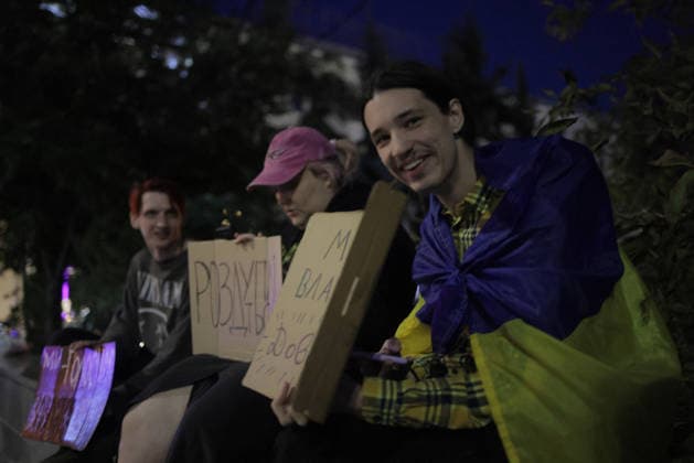 Kharkiv Protesters Demand Reinstatement of Defence Minister Fedorov - Ukraine Young protesters holding cardboard signs — one reading ???????? (Ukrainian: Wake up ) and another partially reading ???...??? — sit draped in a Ukrainian flag at Freedom Square in Kharkiv, Ukraine, on August 14, 2026. The rally was part of ongoing nationwide demonstrations demanding the reinstatement of Mykhailo Fedorov as Minister of Defence, with approximately 500 Kharkiv residents joining the action that evening, organizers said. Photo by Yevhen Titov ABACAPRESS.COM Kharkiv Kharkiv Oblast Ukraine  Copyright: xTitovxYevhen ABACAx