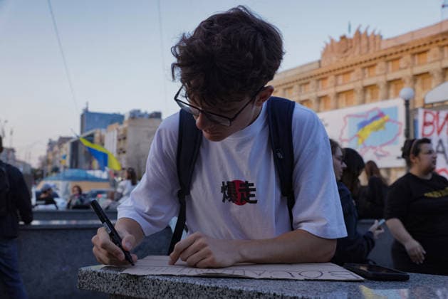 Kharkiv Protesters Demand Reinstatement of Defence Minister Fedorov - Ukraine A young man writes on a cardboard sign at a protest rally at Freedom Square (Ploshcha Svobody) in Kharkiv, Ukraine, on August 14, 2026. Demonstrators gathered to demand the reinstatement of Mykhailo Fedorov as Minister of Defence, marking the 29th day of nationwide protests against President Zelensky s decision to dismiss him; a Ukrainian flag and a banner showing a map of Ukraine are visible among the crowd. Photo by Yevhen Titov ABACAPRESS.COM Kharkiv Kharkiv Oblast Ukraine  Copyright: xTitovxYevhen ABACAx