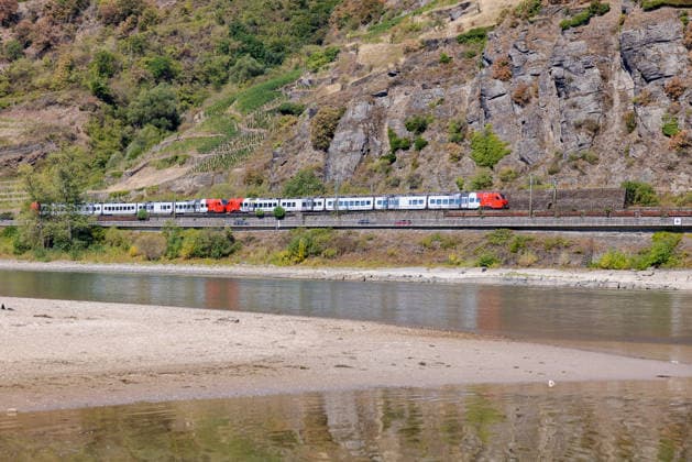 Niedrigwasser am Rhein nach langer Dürrephase, Kaub, 15.08.2026 Ein Regionalzug mit rot-weißen Triebköpfen fährt entlang eines Flussufers, an dem durch Niedrigwasser breite Sand- und Kiesbänke freiliegen. Die bewaldeten und teils terrassierten Hänge im Hintergrund spiegeln sich im ruhigen Wasser. Kaub Rheinland-Pfalz Deutschland *** Low water levels on the Rhine following a long drought, Kaub, August 15, 2026 A regional train with red-and-white power cars travels along a riverbank where low water levels have exposed wide sand and gravel banks. The forested and partly terraced slopes in the background are reflected in the calm water. Kaub, Rhineland-Palatinate, Germany 20260815-286A5662-M4000