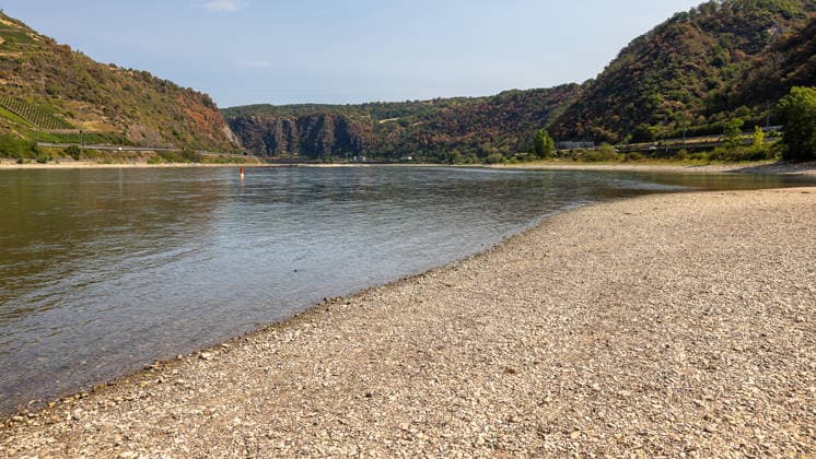 Niedrigwasser am Rhein nach langer Dürrephase, Kaub, 15.08.2026 Ein breiter Kiesstreifen liegt durch anhaltendes Niedrigwasser am Flussufer frei. Bewaldete Hänge säumen das gegenüberliegende Rheinufer bei sommerlichem, wolkenlosem Wetter. Kaub Rheinland-Pfalz Deutschland *** Low water levels on the Rhine following a long period of drought, Kaub, August 15, 2026. A wide strip of gravel is exposed along the riverbank due to persistently low water levels. Wooded slopes line the opposite bank of the Rhine in summery, cloudless weather. Kaub, Rhineland-Palatinate, Germany 20260815-286A5672-M4000