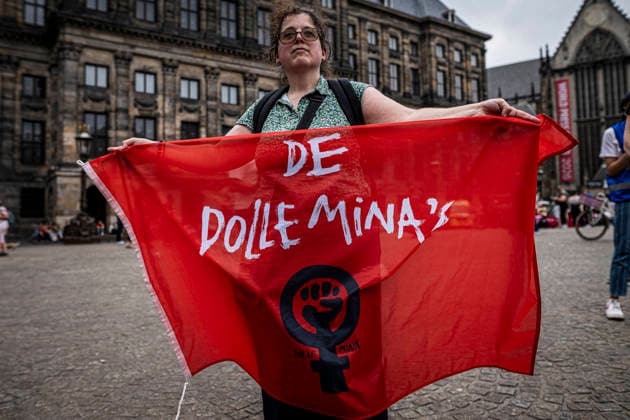 August 15, 2026, Amsterdam, North Holland, The Netherlands Holland: A demonstrator holds a flag for the feminist group De Dolle Mina. August 15, 2026, Amsterdam, The Netherlands. Demonstrators gathered on Dam Square, Amsterdam, in solidarity with Afghan women and girls. The protest marked five years of Taliban rule and demanded access to education for women and girls be restored, and an end to Brussels engagement with the Taliban regime. Amsterdam The Netherlands Holland  - ZUMAp202 20260815_zip_p202_008 Copyright: xJamesxPetermeierx
