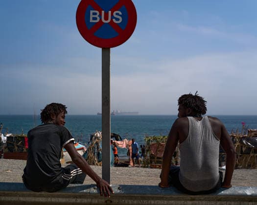 (260815) -- CEUTA, Aug. 15, 2026 -- Irregular migrants sit at the Trampolin Beach in Ceuta, Spain, Aug. 15, 2026. More than 72,000 migrants crossed irregularly into Ceuta from neighboring Morocco on July 30 and 31, according to the Spanish government. Most returned to Morocco later, while thousands remain in the enclave.Security was also tightened along the border ahead of Saturday after calls for another mass crossing circulated on social media. Moroccan security forces intercepted hundreds of migrants attempting to reach the border area, while Ceuta reported no influx on a scale comparable to that seen in late July. ) SPAIN-CEUTA-VIEW MengxDingbo 