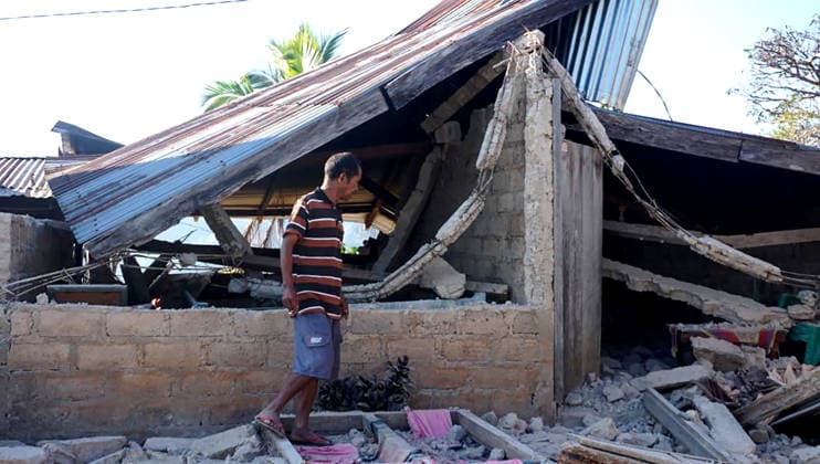 (260816) -- BEIJING, Aug. 16, 2026 -- A man stands near a damaged house after an earthquake on Flores Island, Indonesia, Aug. 15, 2026. The death toll from a 7.7-magnitude earthquake and several strong aftershocks that struck off the coast of Flores Island in eastern Indonesia has risen to 47, the country s National Disaster Mitigation Agency (BNPB) said Saturday. (Photo by Xinhua) XINHUA PHOTOS OF THE DAY Arifin 