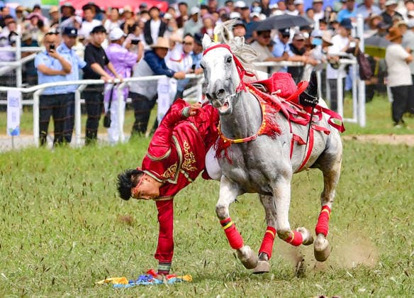 (260816) -- HINGGAN LEAGUE, Aug. 16, 2026 -- A rider demonstrates the equestrian skill of picking up hada on horseback at the opening ceremony of a Nadam fair in Jalaid Banner of Hinggan League, north China s Inner Mongolia Autonomous Region, Aug. 16, 2026. The Nadam fair opened here on Sunday, featuring equestrian performances, songs and dances, instrumental music and traditional folk performances. (Photo by Xinhua) CHINA-INNER MONGOLIA-NADAM FAIR (CN) WangxZheng 
